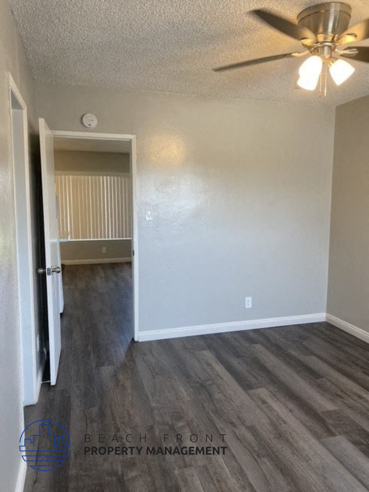 an empty living room with wood flooring and a ceiling fan